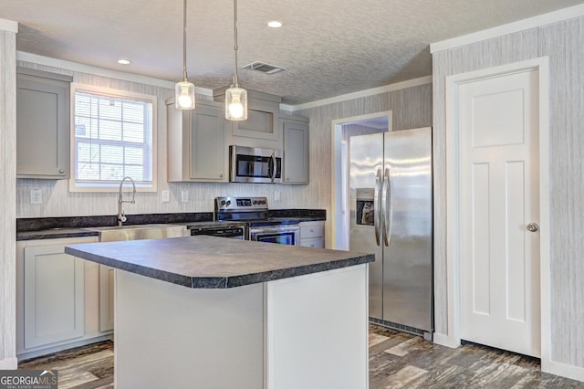 kitchen with a center island, gray cabinetry, hanging light fixtures, and appliances with stainless steel finishes