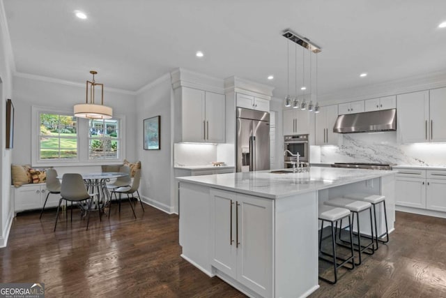 kitchen featuring a center island with sink, pendant lighting, stainless steel built in refrigerator, and white cabinetry