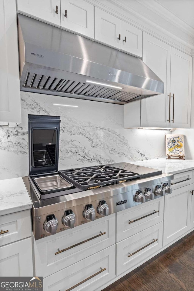 kitchen with dark wood-type flooring, stainless steel gas cooktop, light stone counters, decorative backsplash, and white cabinets