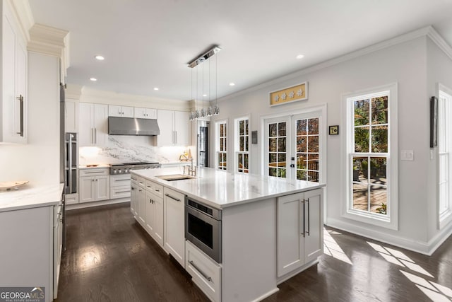 kitchen featuring under cabinet range hood, a sink, white cabinetry, french doors, and appliances with stainless steel finishes