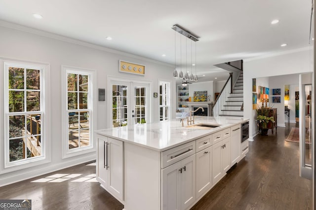 kitchen featuring open floor plan, french doors, crown molding, and a sink