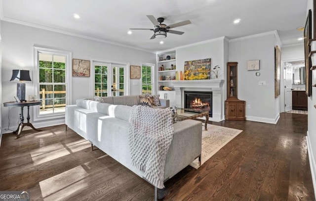 living area featuring crown molding, baseboards, recessed lighting, a glass covered fireplace, and dark wood-style flooring