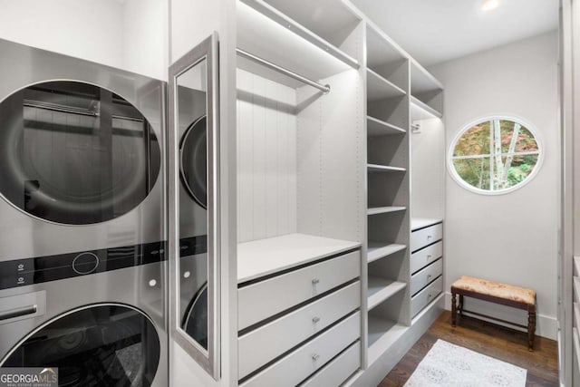 laundry area featuring stacked washer and dryer, dark wood finished floors, and laundry area