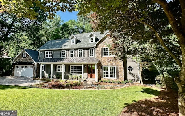 view of front of property featuring a porch, a garage, and a front lawn