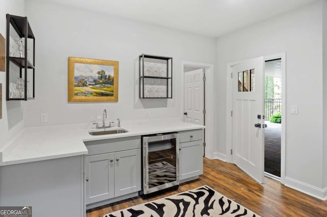 bar featuring baseboards, beverage cooler, dark wood finished floors, wet bar, and a sink