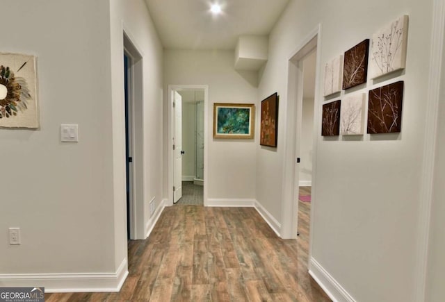 corridor with baseboards and wood finished floors