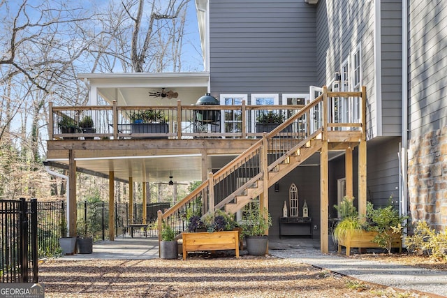 view of exterior entry featuring a deck, a patio area, a ceiling fan, and fence