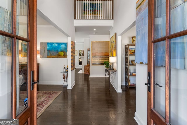 foyer entrance featuring a high ceiling, wood finished floors, and baseboards