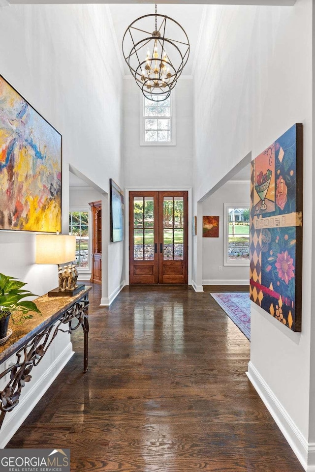 foyer with wood finished floors, french doors, an inviting chandelier, crown molding, and baseboards