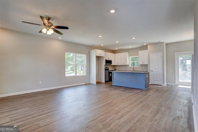 kitchen featuring a kitchen island, white cabinetry, a wealth of natural light, and appliances with stainless steel finishes