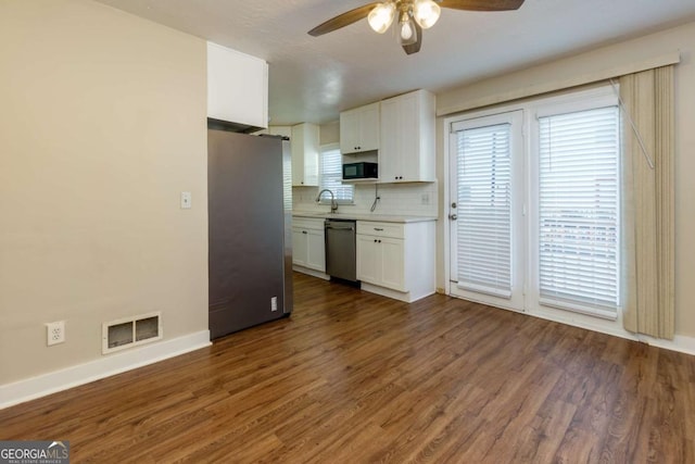 kitchen featuring white cabinets, dark wood-type flooring, stainless steel appliances, and tasteful backsplash