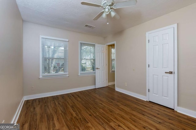 unfurnished bedroom with a textured ceiling, ceiling fan, and dark wood-type flooring