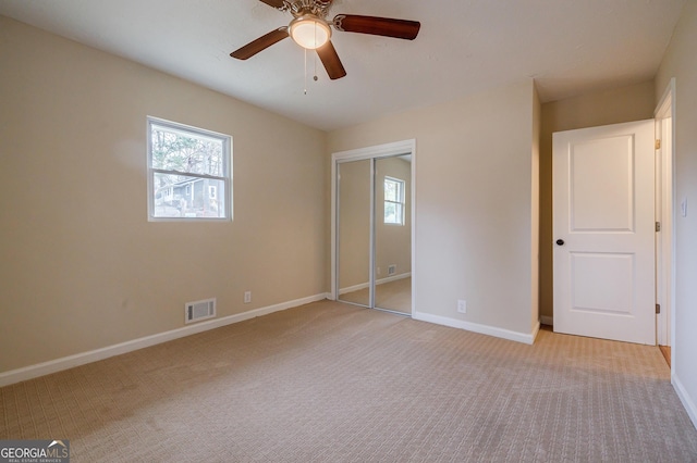 unfurnished bedroom with light carpet, a closet, and ceiling fan