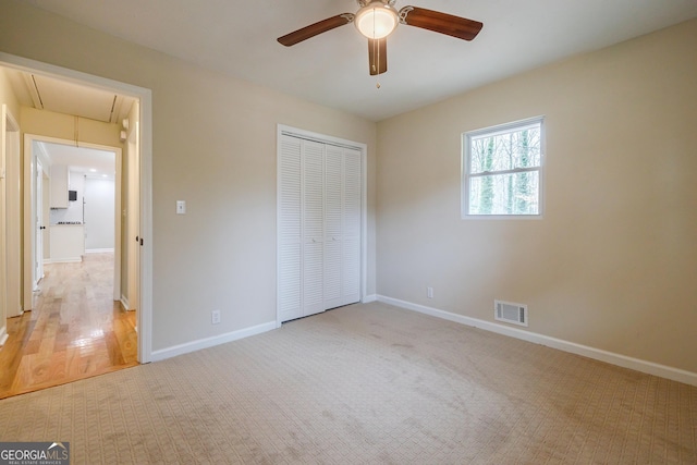 unfurnished bedroom with light colored carpet, a closet, and ceiling fan