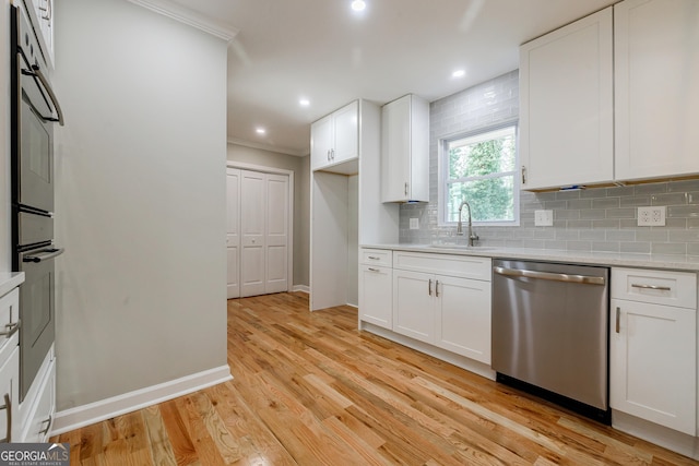 kitchen featuring sink, light hardwood / wood-style flooring, decorative backsplash, appliances with stainless steel finishes, and white cabinetry