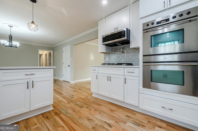 kitchen featuring decorative backsplash, appliances with stainless steel finishes, ornamental molding, decorative light fixtures, and white cabinets