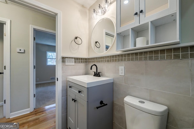 bathroom with hardwood / wood-style floors, vanity, toilet, and tile walls