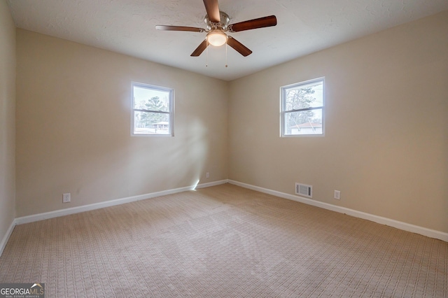 carpeted spare room featuring ceiling fan and a wealth of natural light