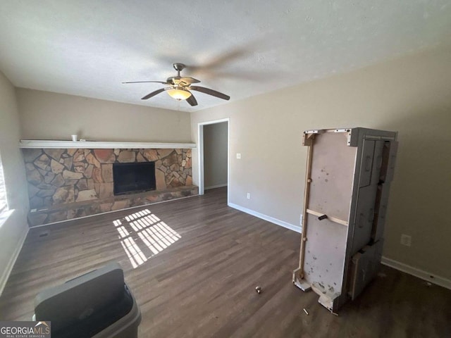 unfurnished living room with ceiling fan, a fireplace, dark wood-type flooring, and a textured ceiling