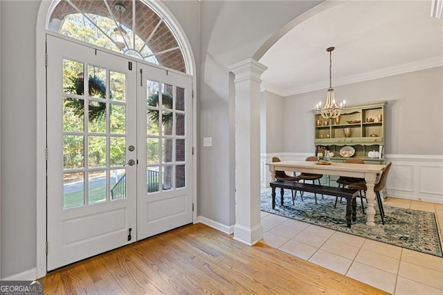 doorway to outside featuring arched walkways, crown molding, french doors, ornate columns, and a notable chandelier