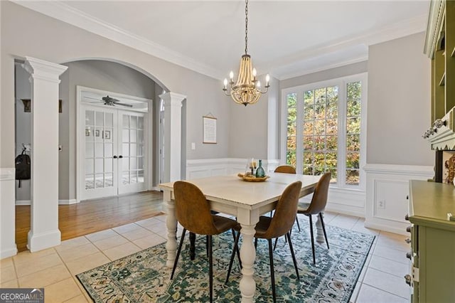 dining area with arched walkways, light tile patterned floors, a decorative wall, decorative columns, and crown molding