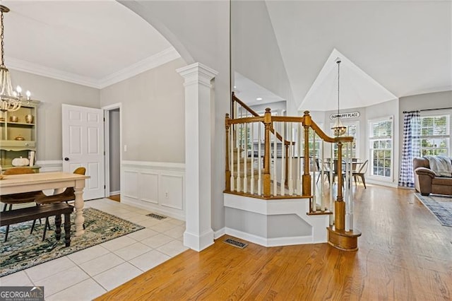 interior space featuring arched walkways, a notable chandelier, wood finished floors, visible vents, and ornate columns