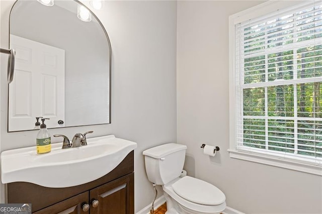 bathroom with toilet, vanity, and baseboards