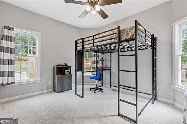 bedroom with multiple windows, light carpet, and baseboards