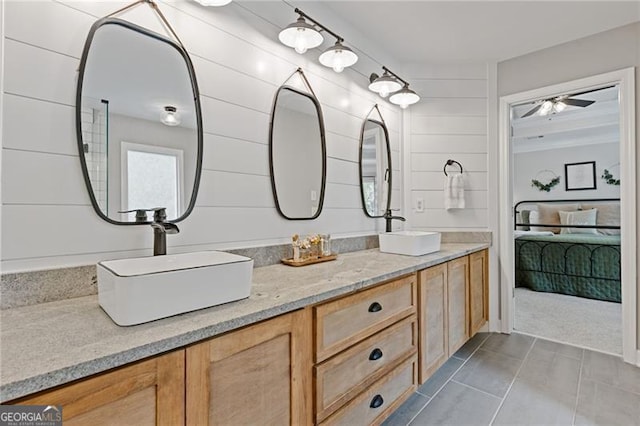 full bathroom with ensuite bathroom, double vanity, wood walls, and a sink