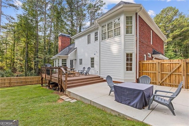 back of house featuring a patio, a fenced backyard, a lawn, a wooden deck, and a chimney