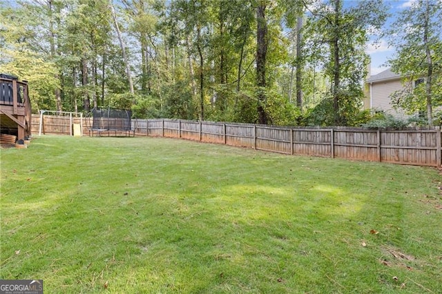 view of yard with a trampoline and a fenced backyard