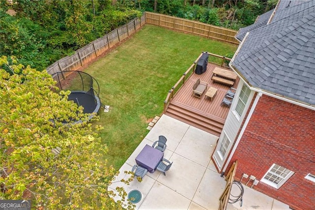 view of yard featuring a trampoline, a patio area, a fenced backyard, and a deck