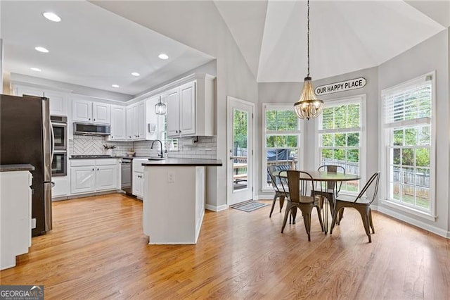 kitchen with a chandelier, white cabinetry, appliances with stainless steel finishes, dark countertops, and pendant lighting