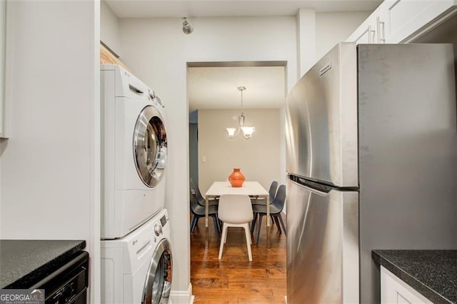 washroom featuring a notable chandelier, dark hardwood / wood-style flooring, and stacked washer / dryer