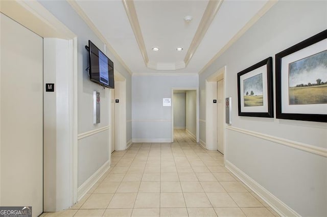 hall featuring a raised ceiling, light tile patterned floors, crown molding, and elevator