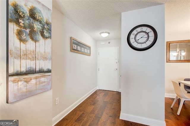 hallway with a textured ceiling and dark hardwood / wood-style flooring