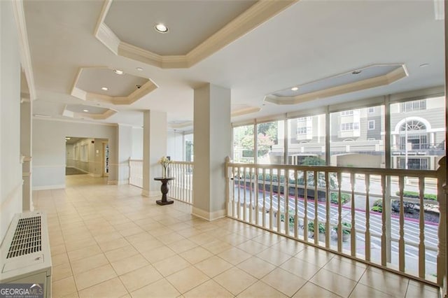 interior space featuring a tray ceiling, light tile patterned floors, and ornamental molding