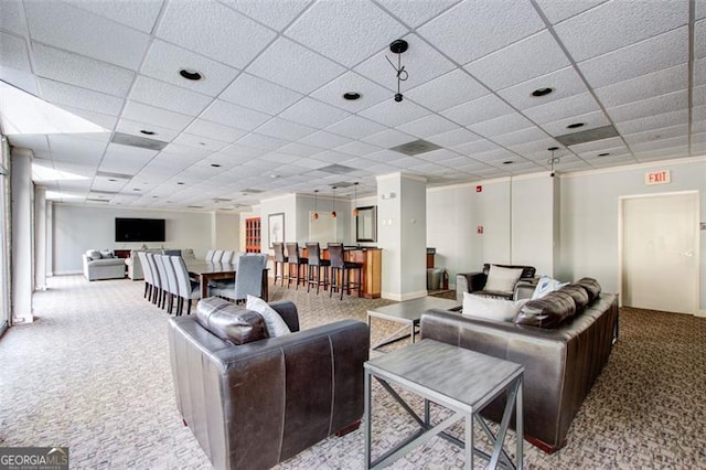 living room featuring a drop ceiling and carpet floors