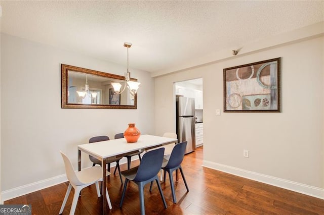 dining room with hardwood / wood-style flooring, a textured ceiling, and an inviting chandelier