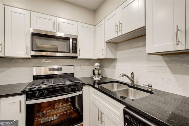 kitchen featuring backsplash, stainless steel appliances, sink, dark stone countertops, and white cabinetry