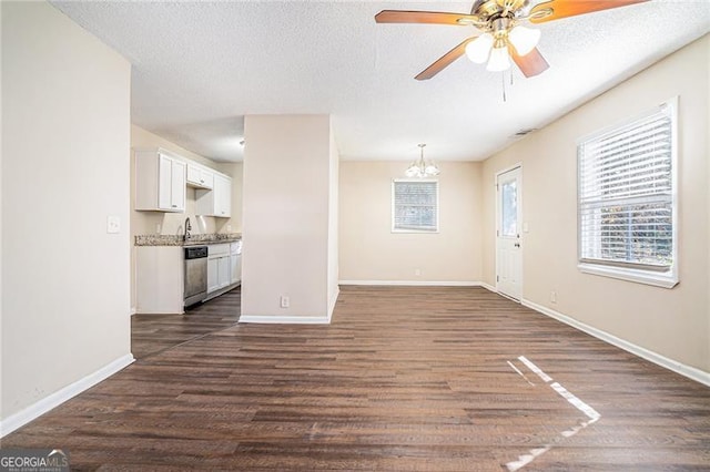 unfurnished living room featuring a textured ceiling, ceiling fan with notable chandelier, dark hardwood / wood-style floors, and sink