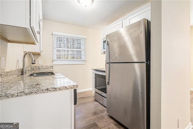 kitchen featuring white cabinets, sink, a textured ceiling, light stone counters, and stainless steel appliances