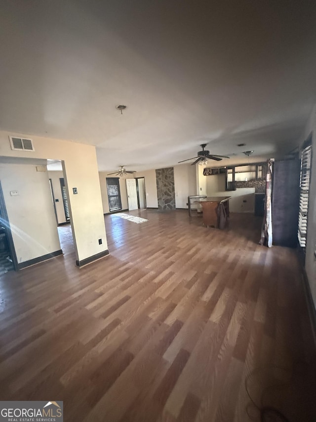 unfurnished living room featuring ceiling fan and dark wood-type flooring