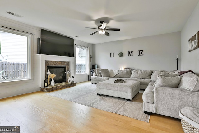 living room with ceiling fan, a fireplace, and light wood-type flooring