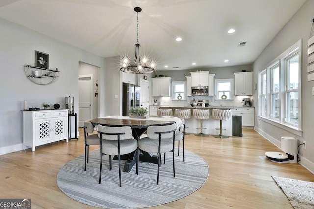 dining space featuring light hardwood / wood-style flooring and an inviting chandelier