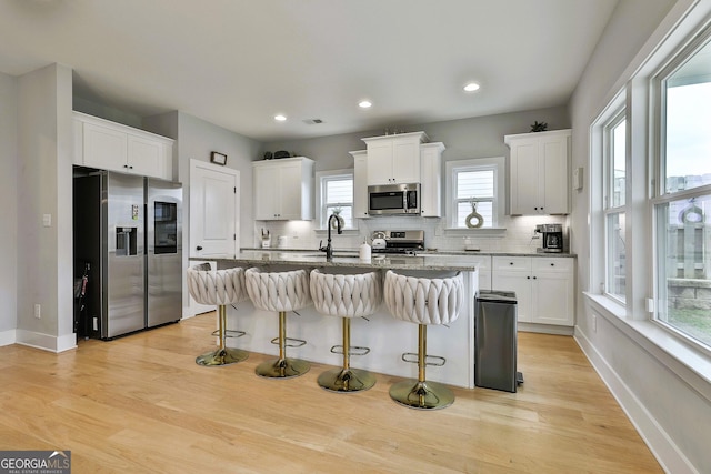 kitchen featuring a kitchen bar, dark stone counters, stainless steel appliances, a center island, and white cabinetry