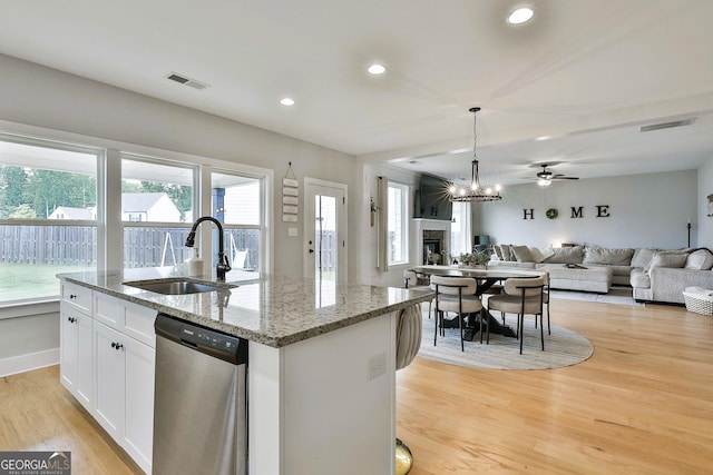 kitchen featuring dishwasher, a center island with sink, sink, light stone countertops, and white cabinetry