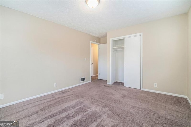 unfurnished bedroom with carpet flooring, a textured ceiling, and a closet