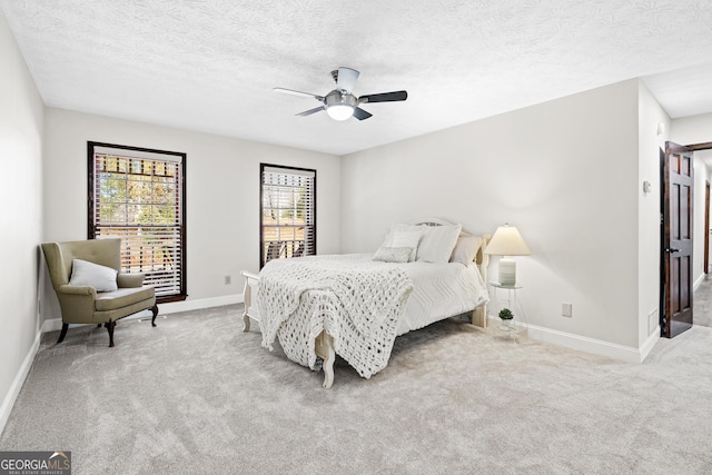 bedroom with a textured ceiling, light colored carpet, and ceiling fan