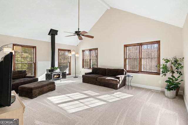 living room with light carpet, plenty of natural light, ceiling fan, and a wood stove